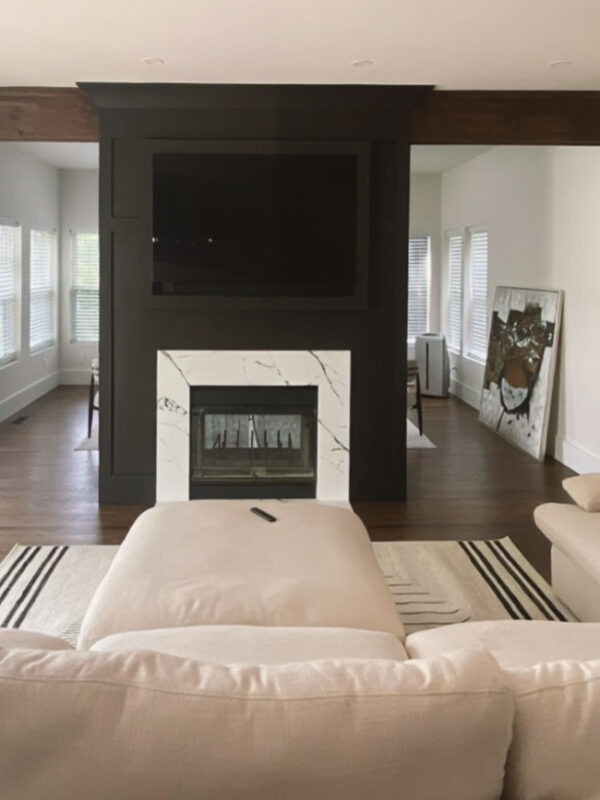 Finished fireplace with a black feature wall and marble surround, creating the focal point of the living room