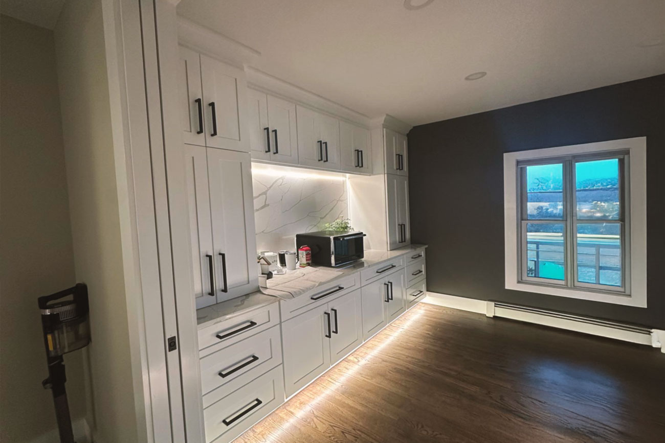 Kitchen corner showcasing custom cabinetry, countertops, a modern oven, and under-cabinet lighting.